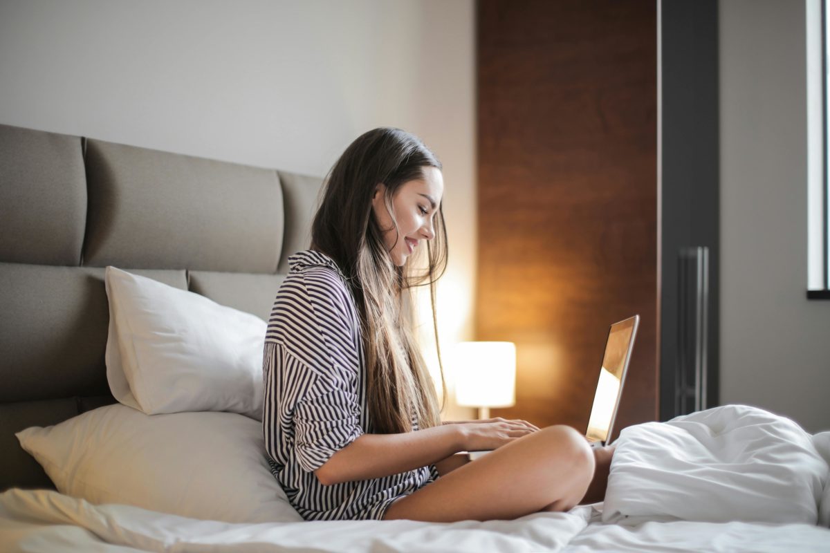 Foto von Andrea Piacquadio: https://www.pexels.com/de-de/foto/seitenansicht-foto-der-lachelnden-frau-in-einem-schwarz-weiss-gestreiften-oberteil-das-auf-einem-bett-sitzt-wahrend-man-einen-laptop-benutzt-3765035/